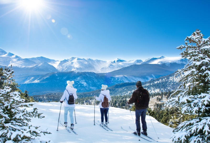 A trio of friends enjoying the Estes Park winter while cross country skiing atop a mountain hillside.